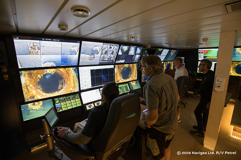 Expedition members participating in the 2018 ROV examination of AE1 watch live footage of the submarine’s stern torpedo tube in the control room aboard the research vessel Petrel. Image: Paul G. Allen, Find AE1 Ltd., ANMM and Curtin University. Copyright, Navigea Ltd.
