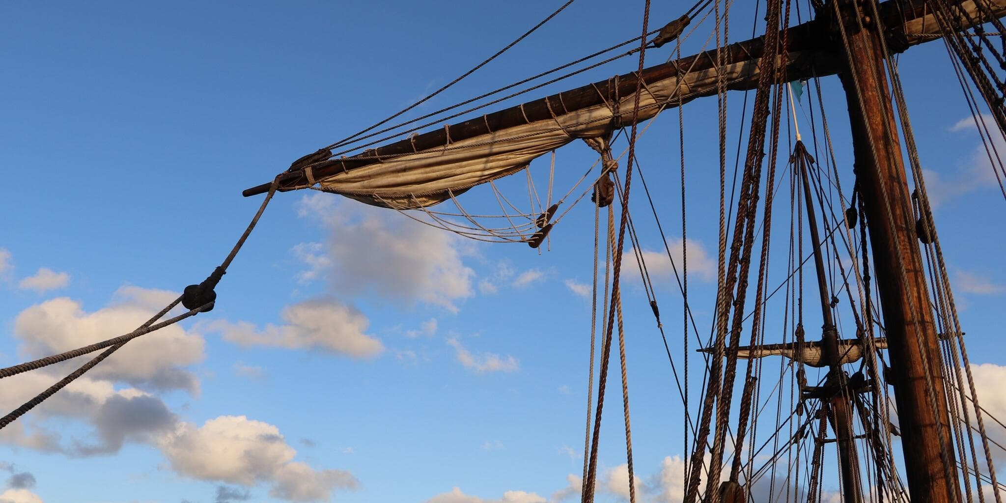 tall ship masts and rope with blue sky and clouds