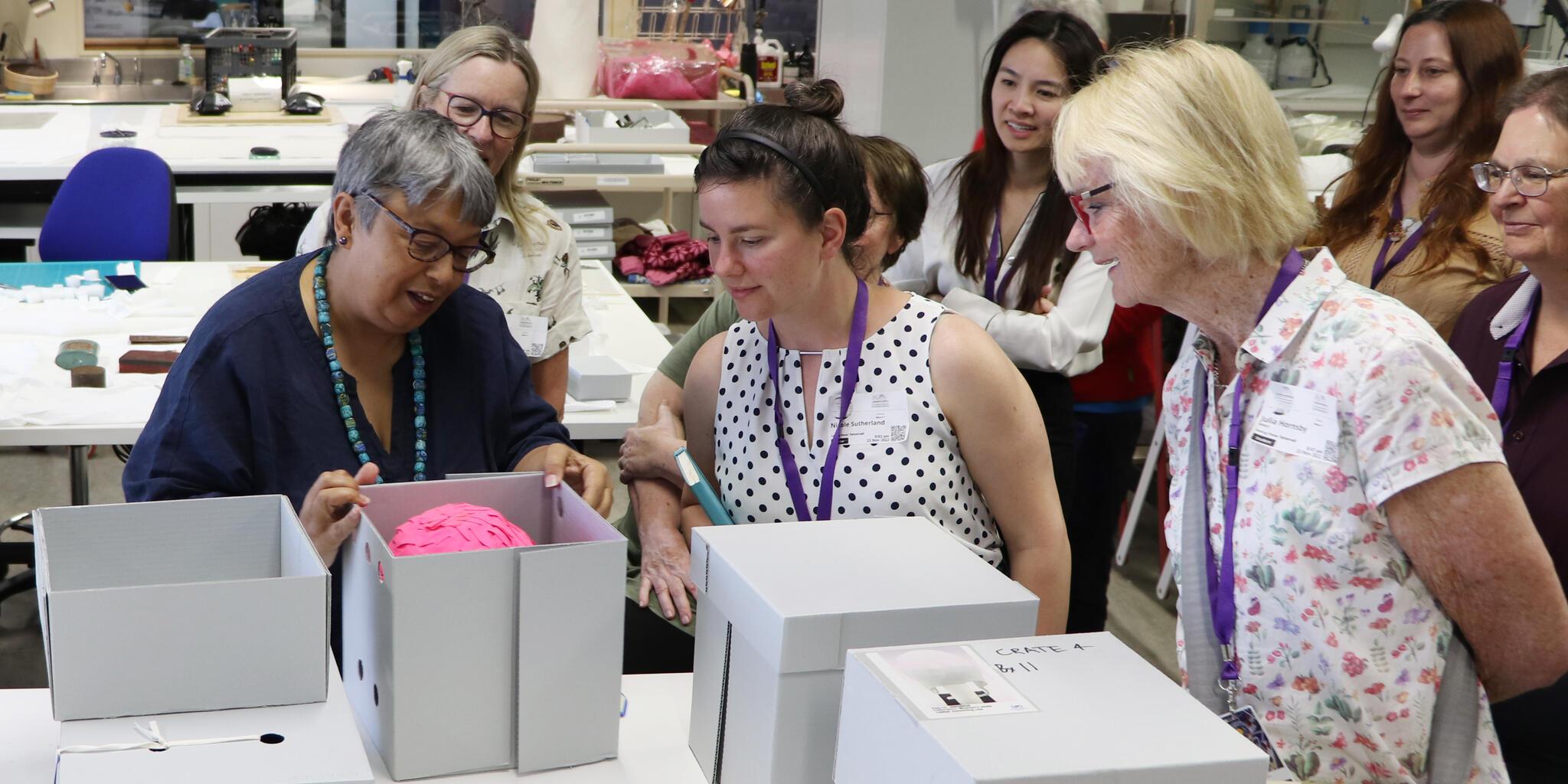 Group of women looking in white boxes in a conservation lab. 