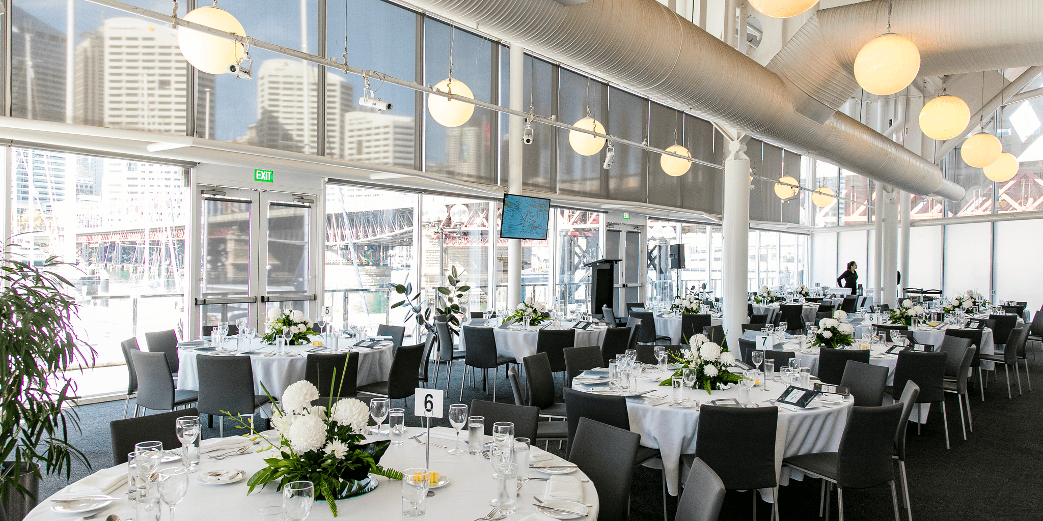 photo of a light filled event space with large round tables set for a formal event. 