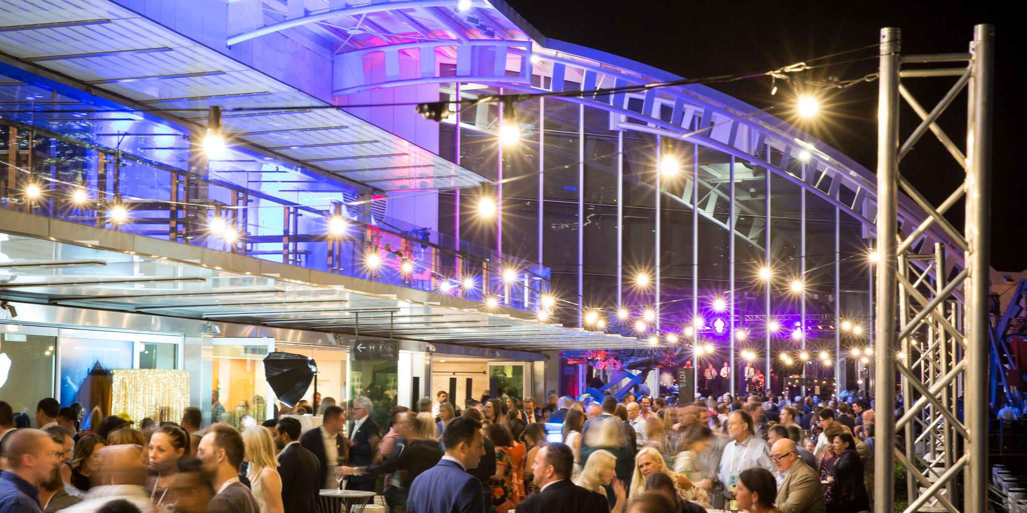 The museum precinct filled with crowds during a corporate event at night