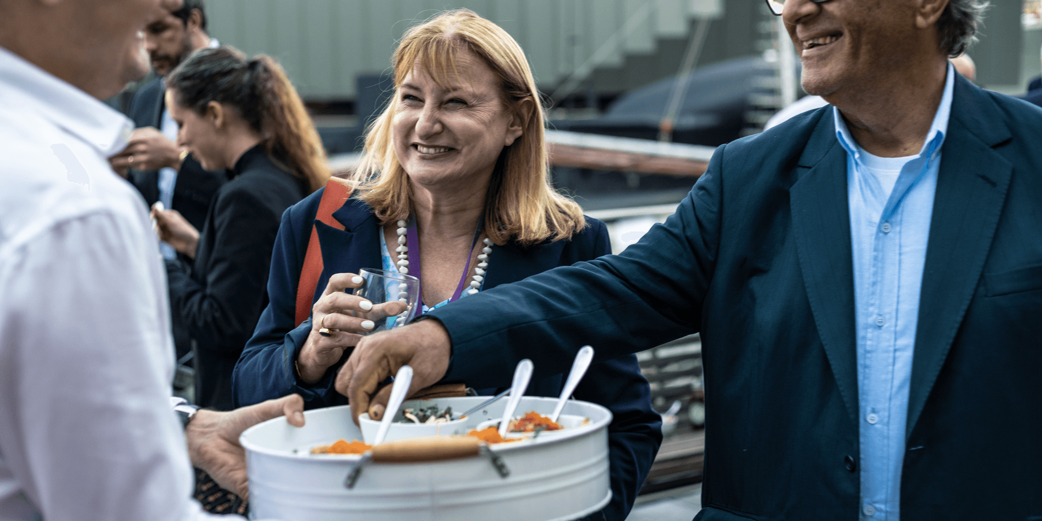 2 guests, a male and female, at an event taking food from a server. 