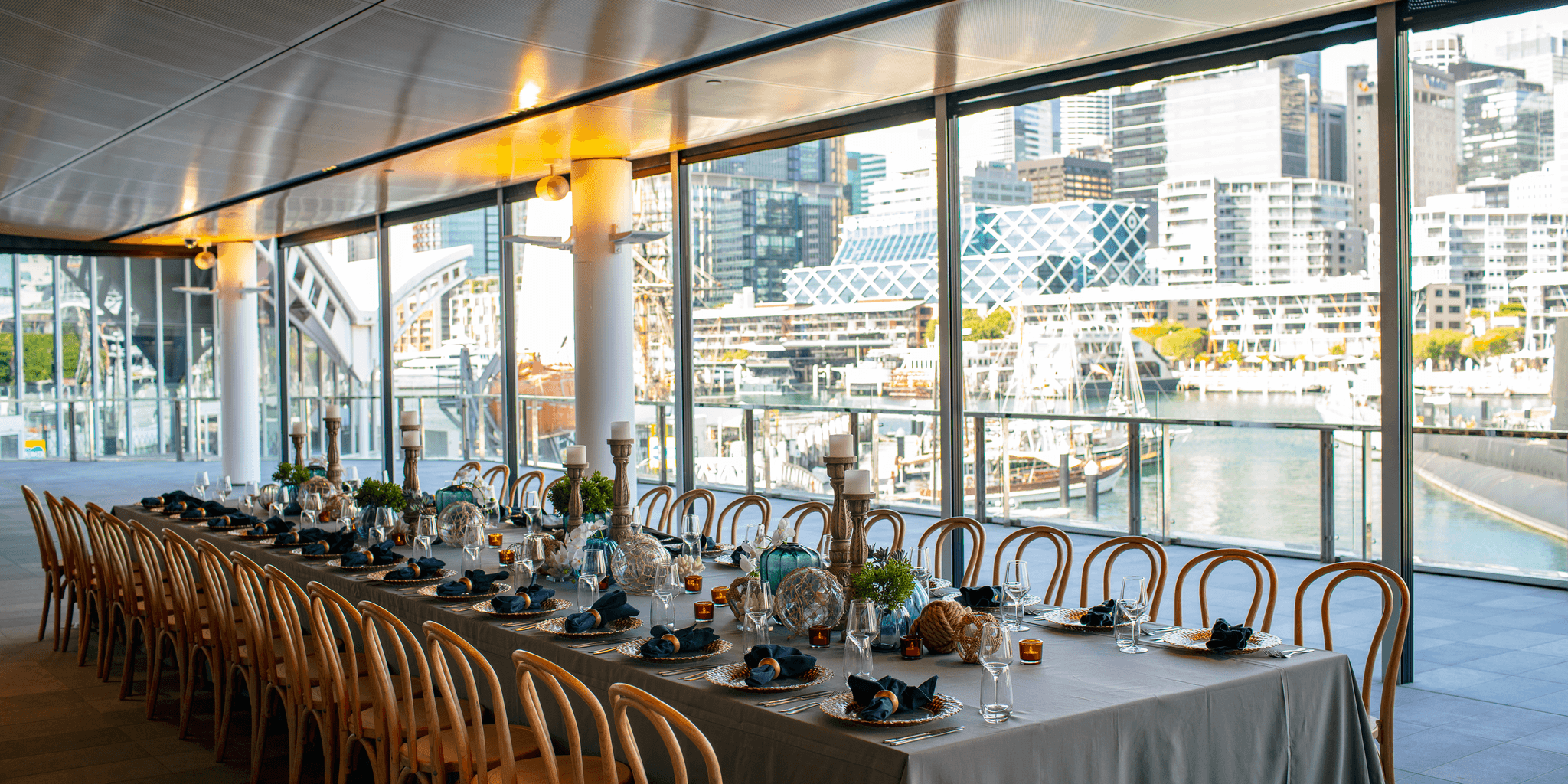 Photo of interior space with a long table set for a formal event, with an open balcony in the background.