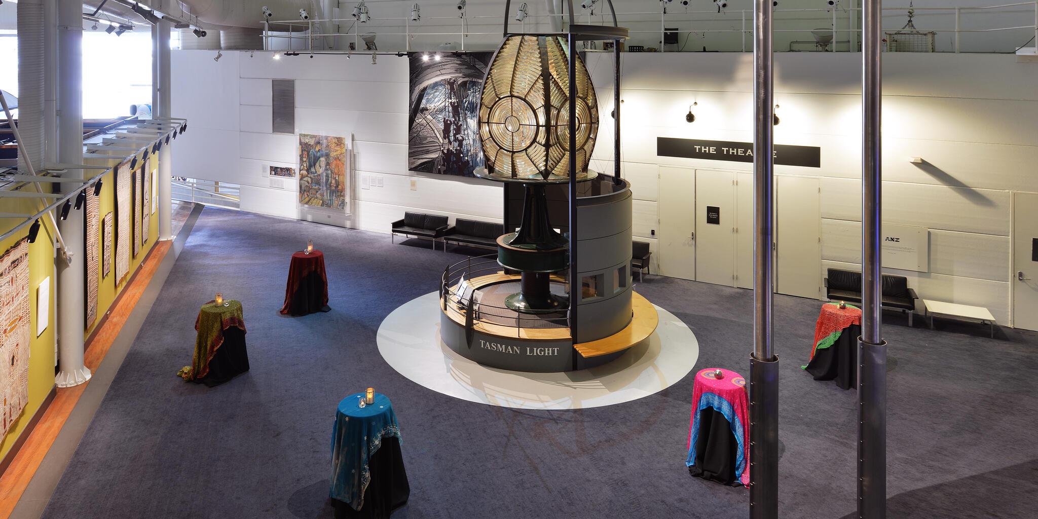 photo taken from above of a large event space with a large lighthouse lens in the middle of the room. 