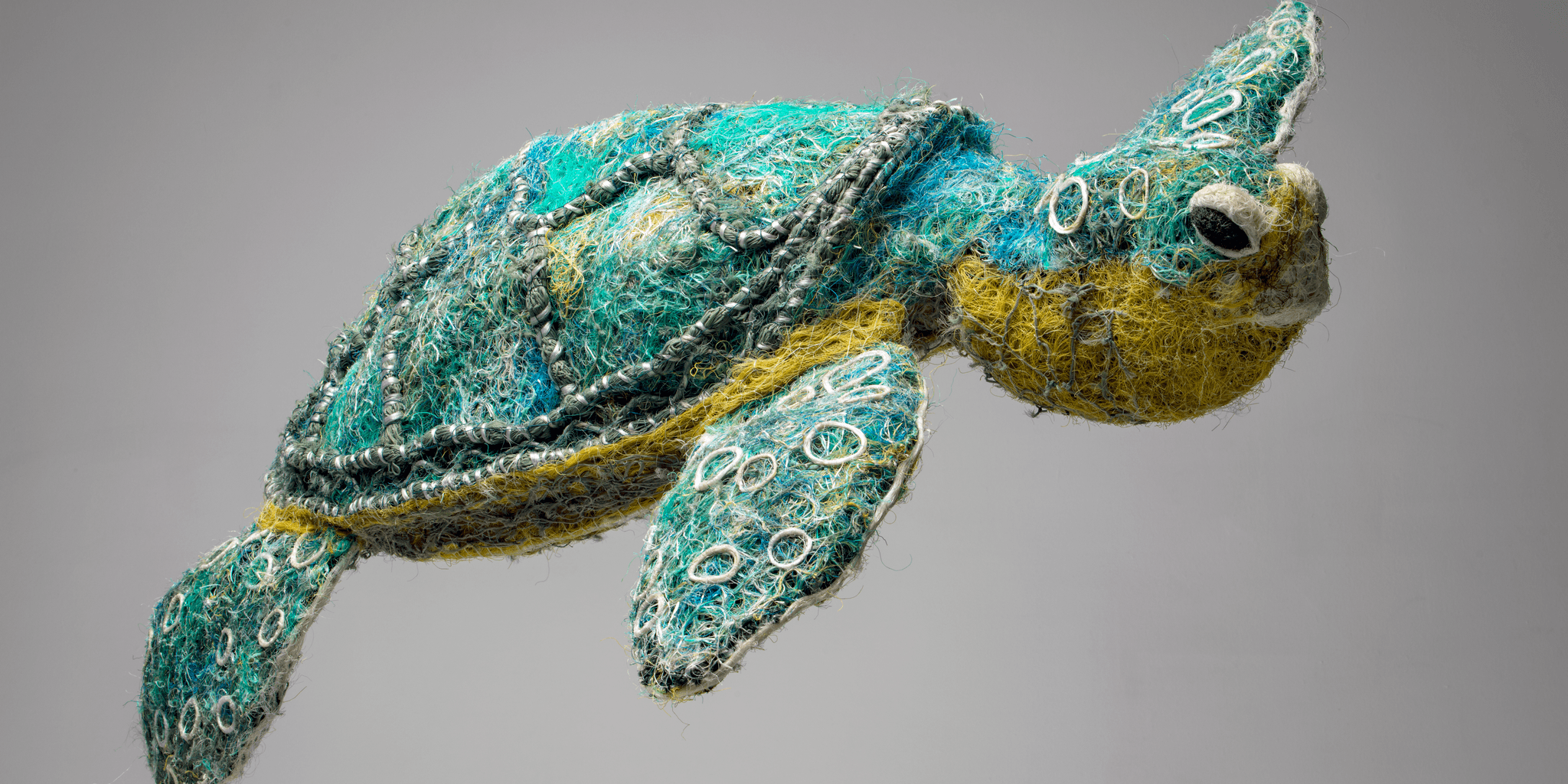 A turtle sculpture made of green and yellow fishing line and netting.