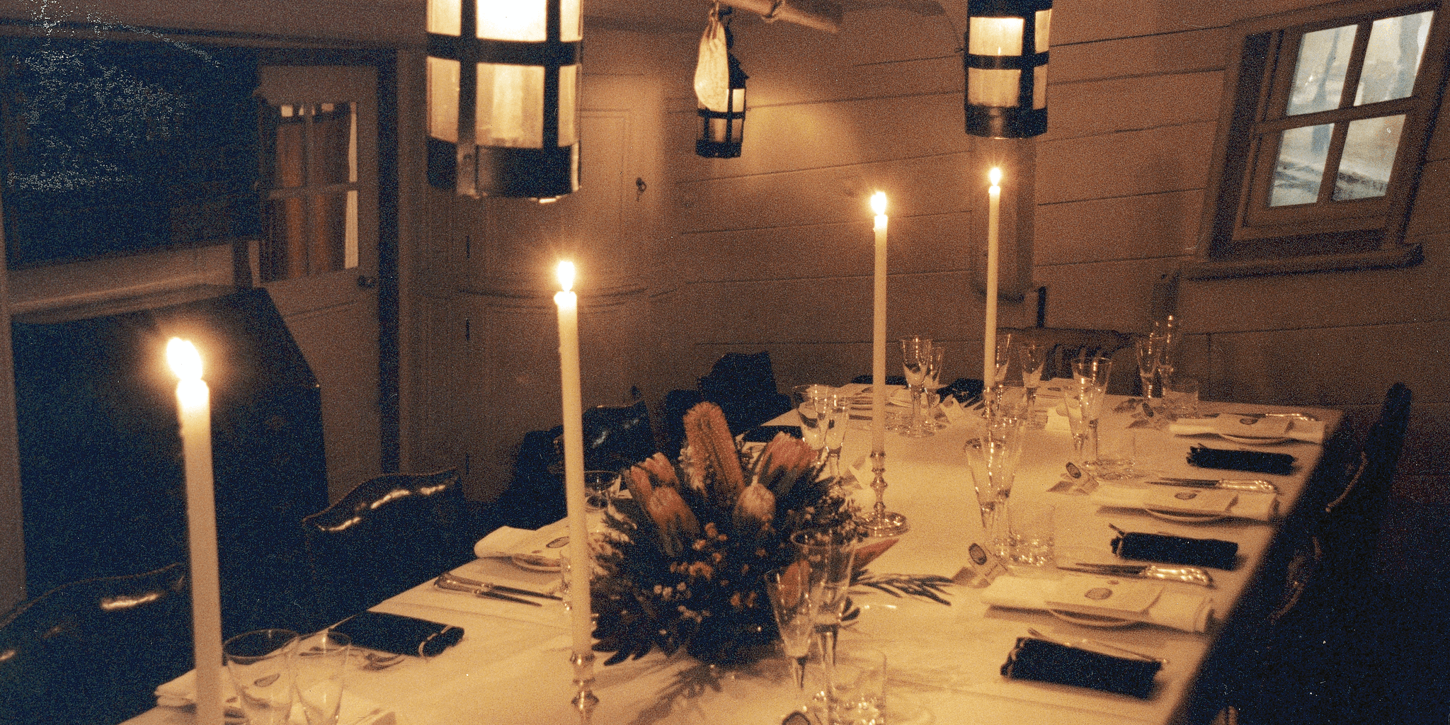 Views of tall ship interior featuring dining table with place settings and candles.