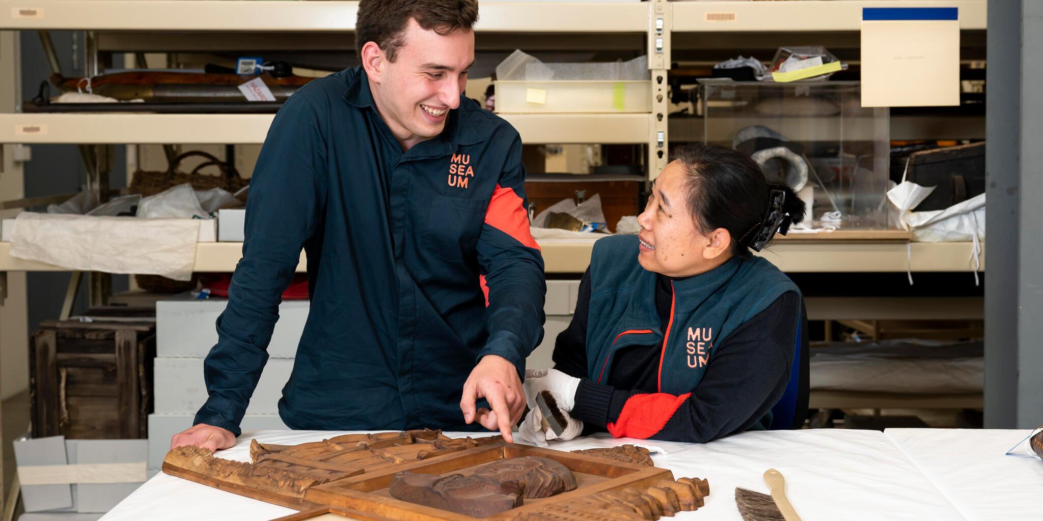 2 museum volunteers, one male one femaile, dusting a collection object in the museum's object stores.