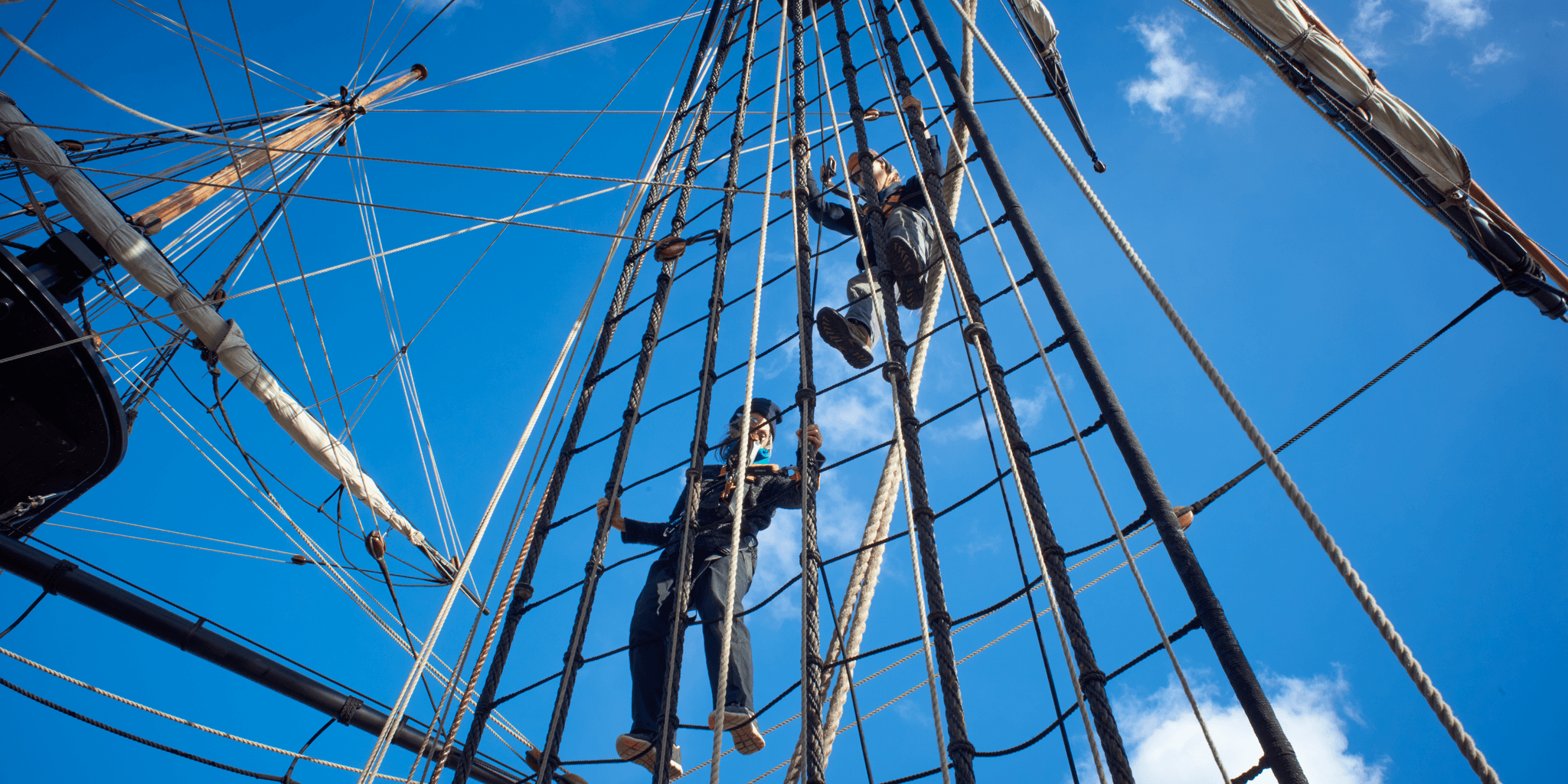 Ropes mast rigging. Two crew members climbing up.