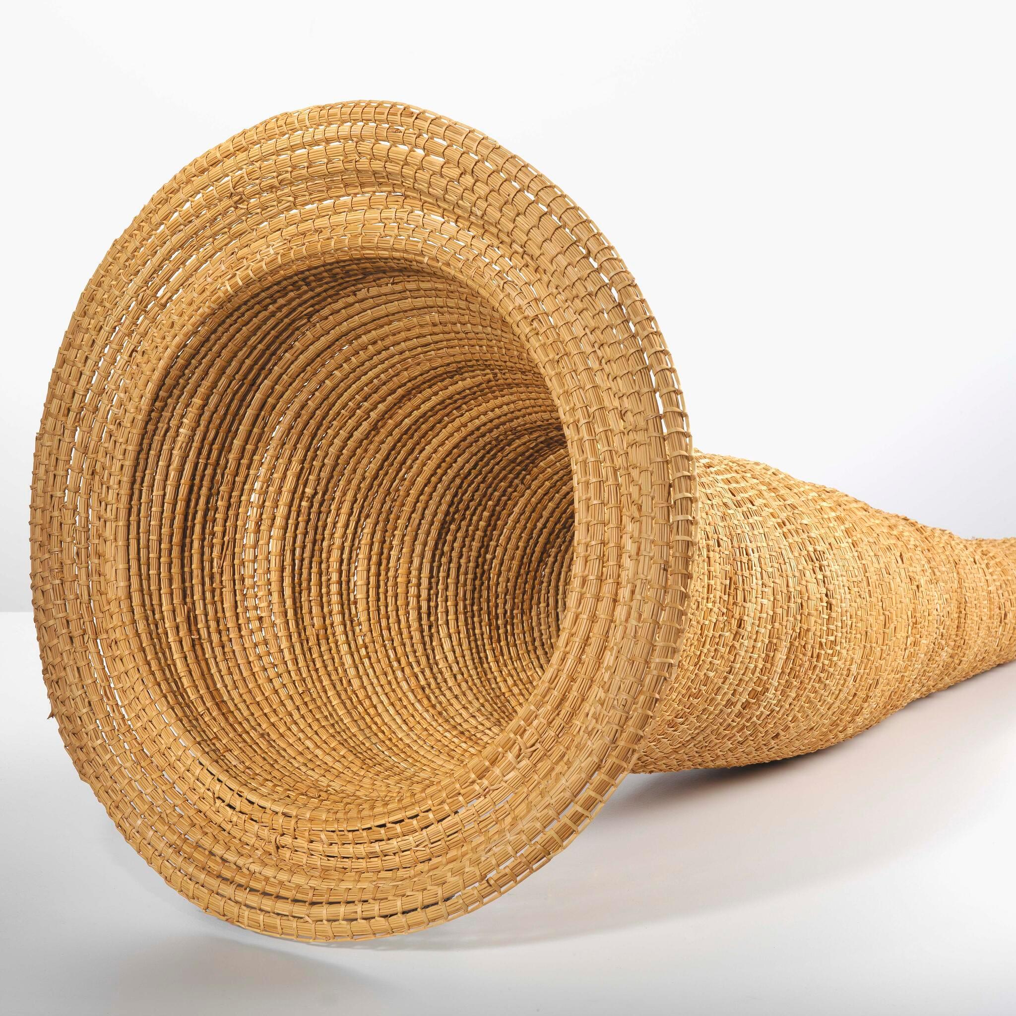 A photograph looking into the open mouth of a traditional eel trap made of river reeds