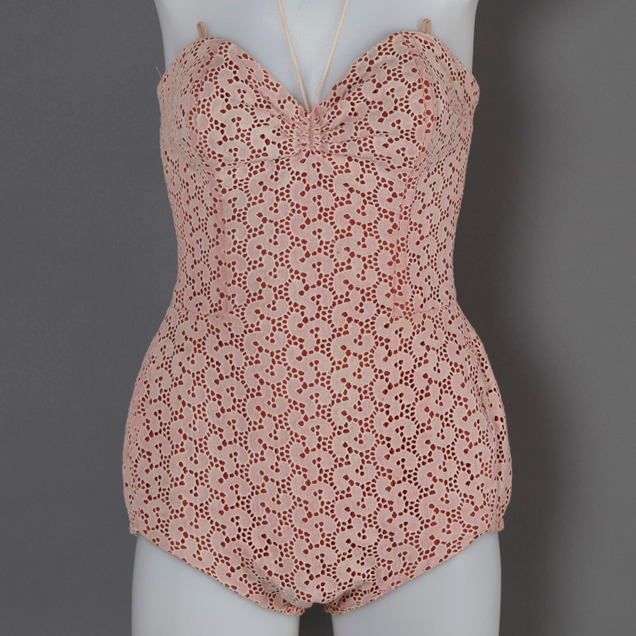 Image of a one peice swimsuit made of lace with an orange background.