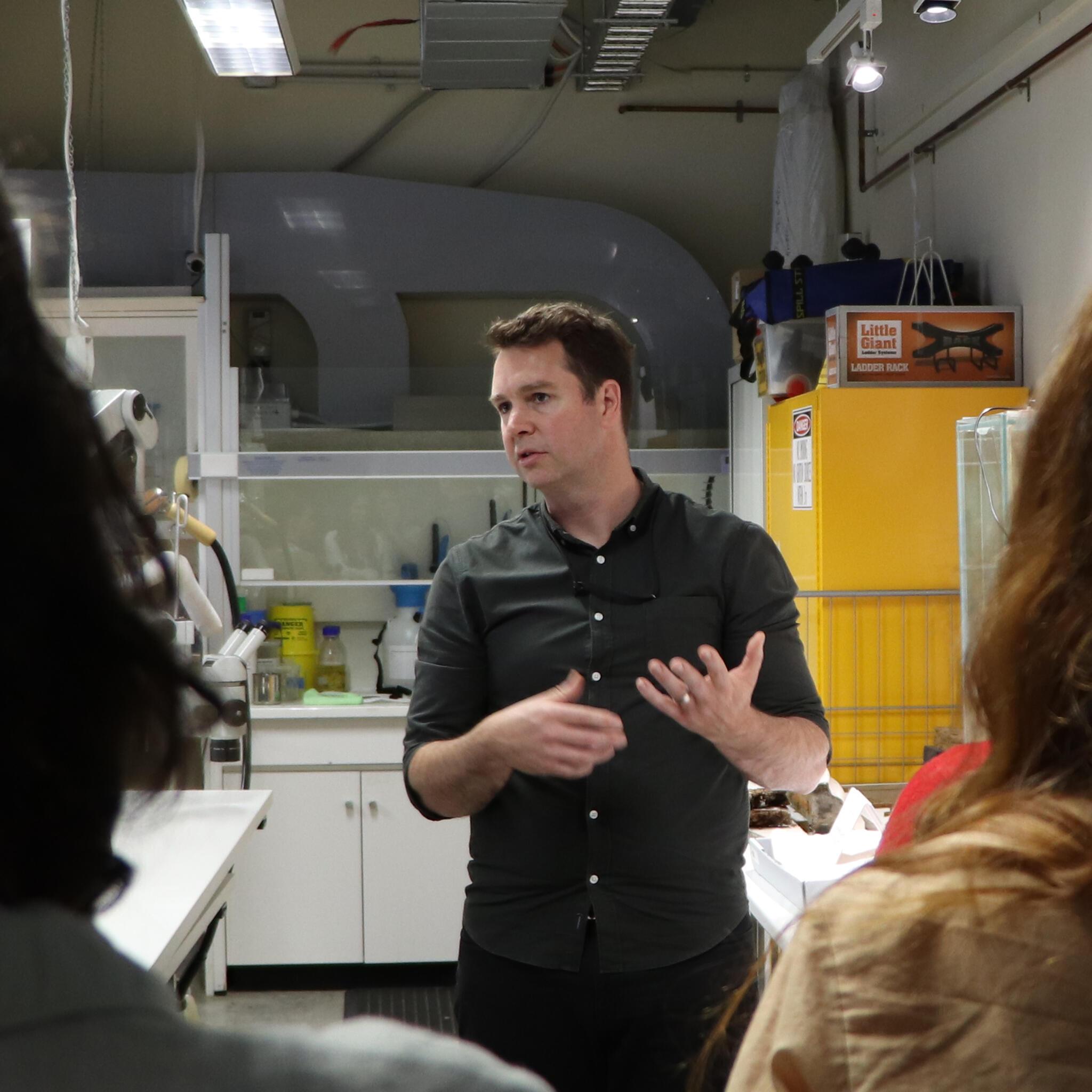 A man in a dark shirt standing in a lab