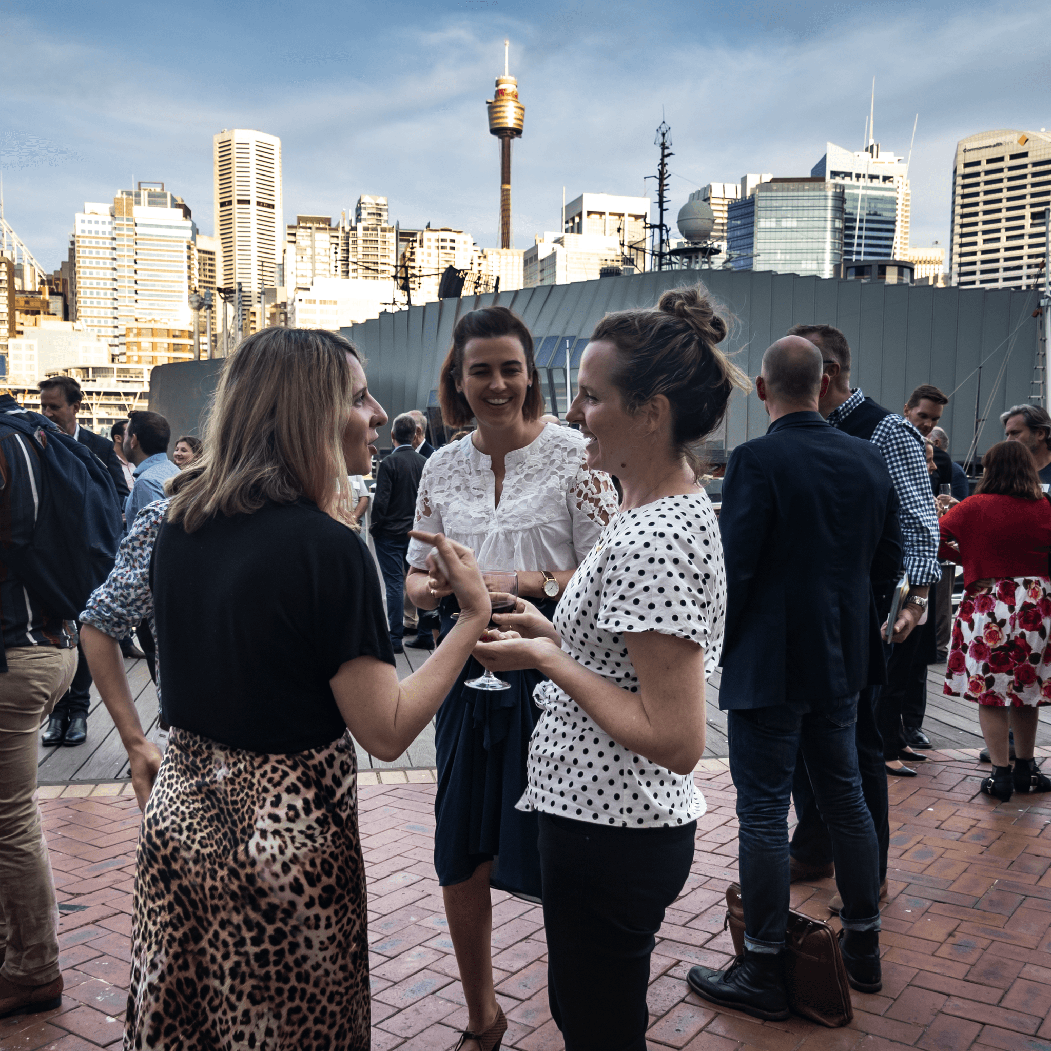 Event guests mingling. Cityscape background.