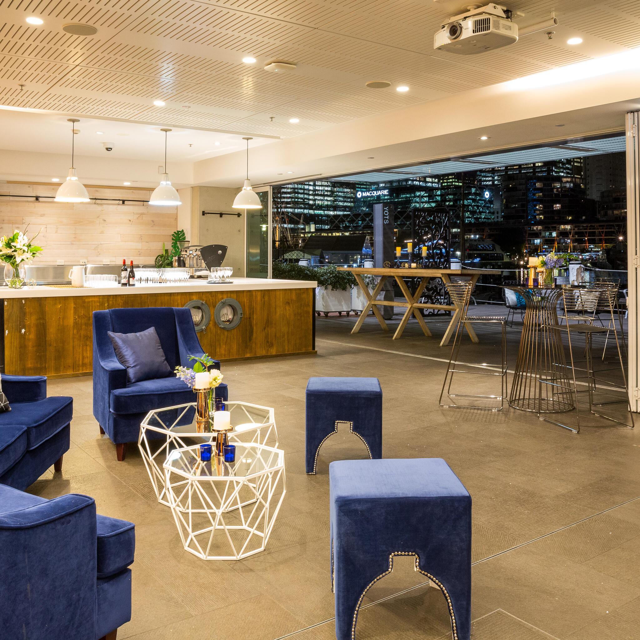 photo of interior space with blue couches. coffee tables and a bar. 