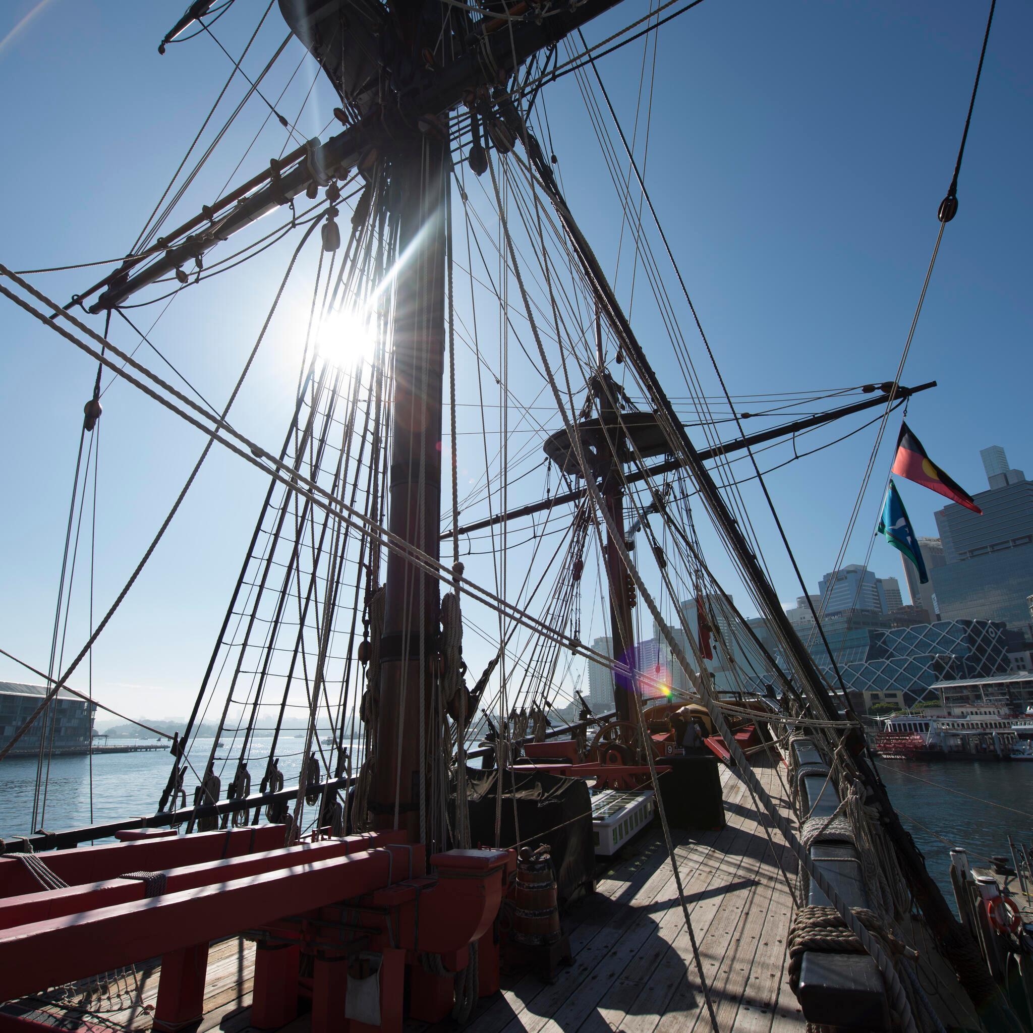 photo on the deck of a tall ship, looking up at the mast with a blue sky.