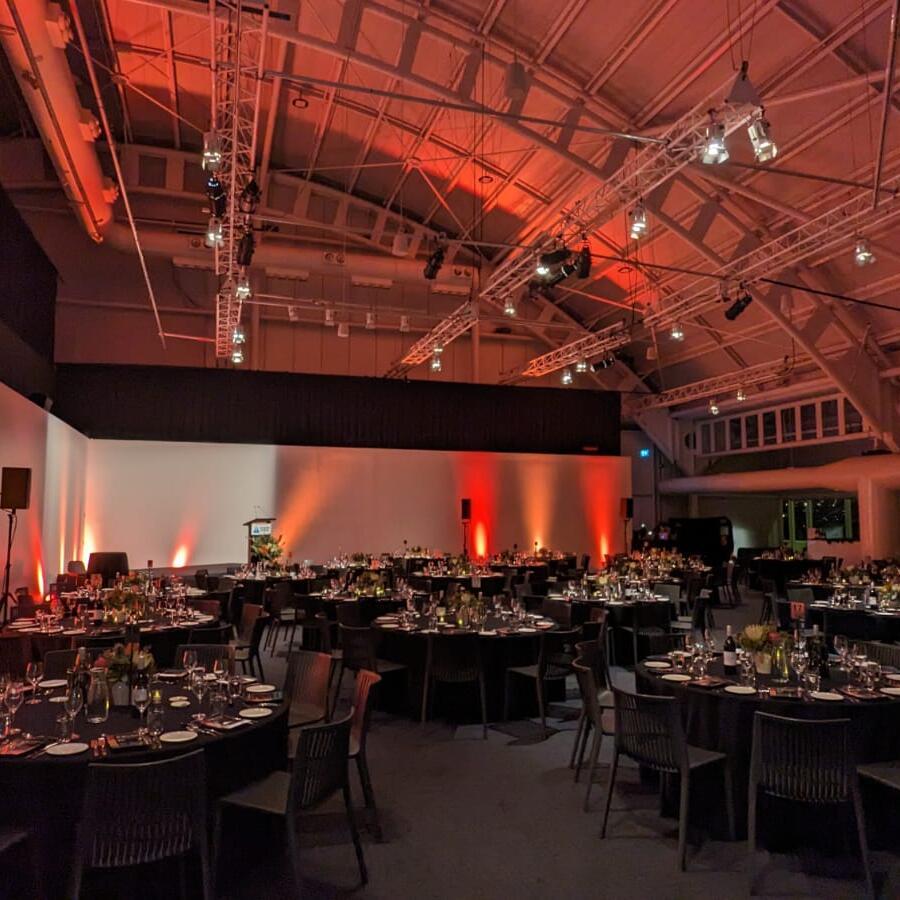 photo of an interior of a large event space, with tables and a red lighting scheme. 