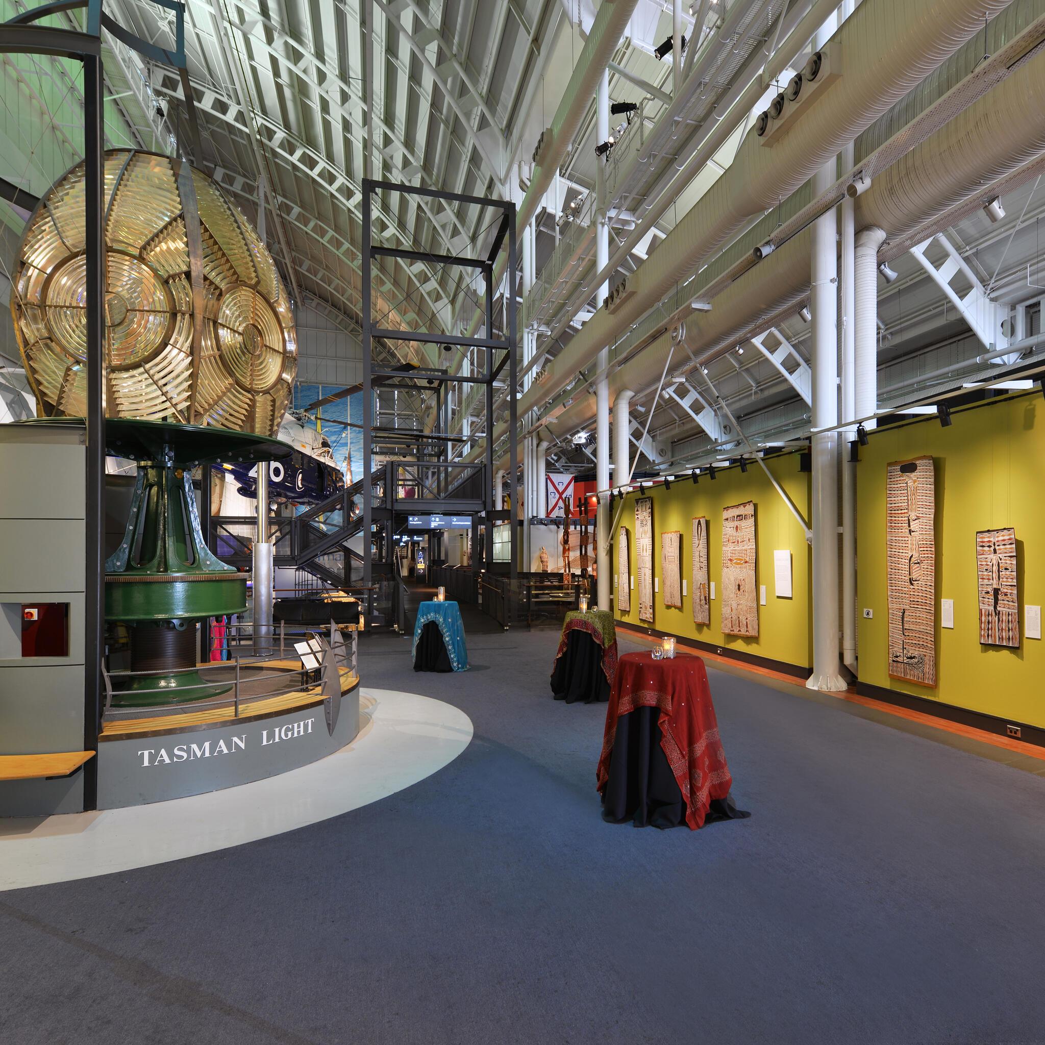 photo of interior space with a lighthouse lens on the left and a wall of first nations art on the left