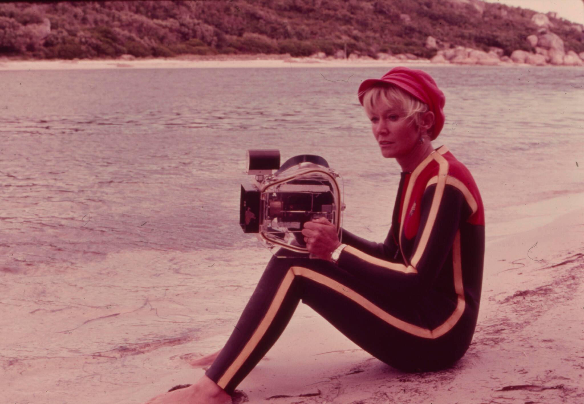 Valerie on a beach holding a camera