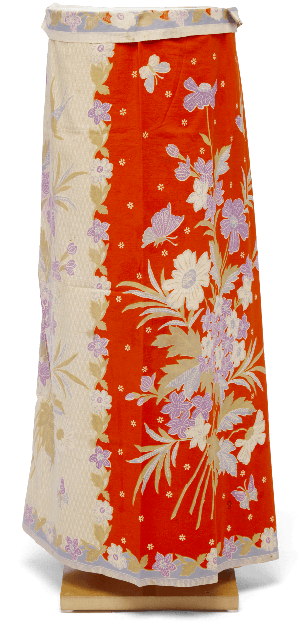 Orange ad cream sarong with pastel flowers. It is on a wooden stand. 