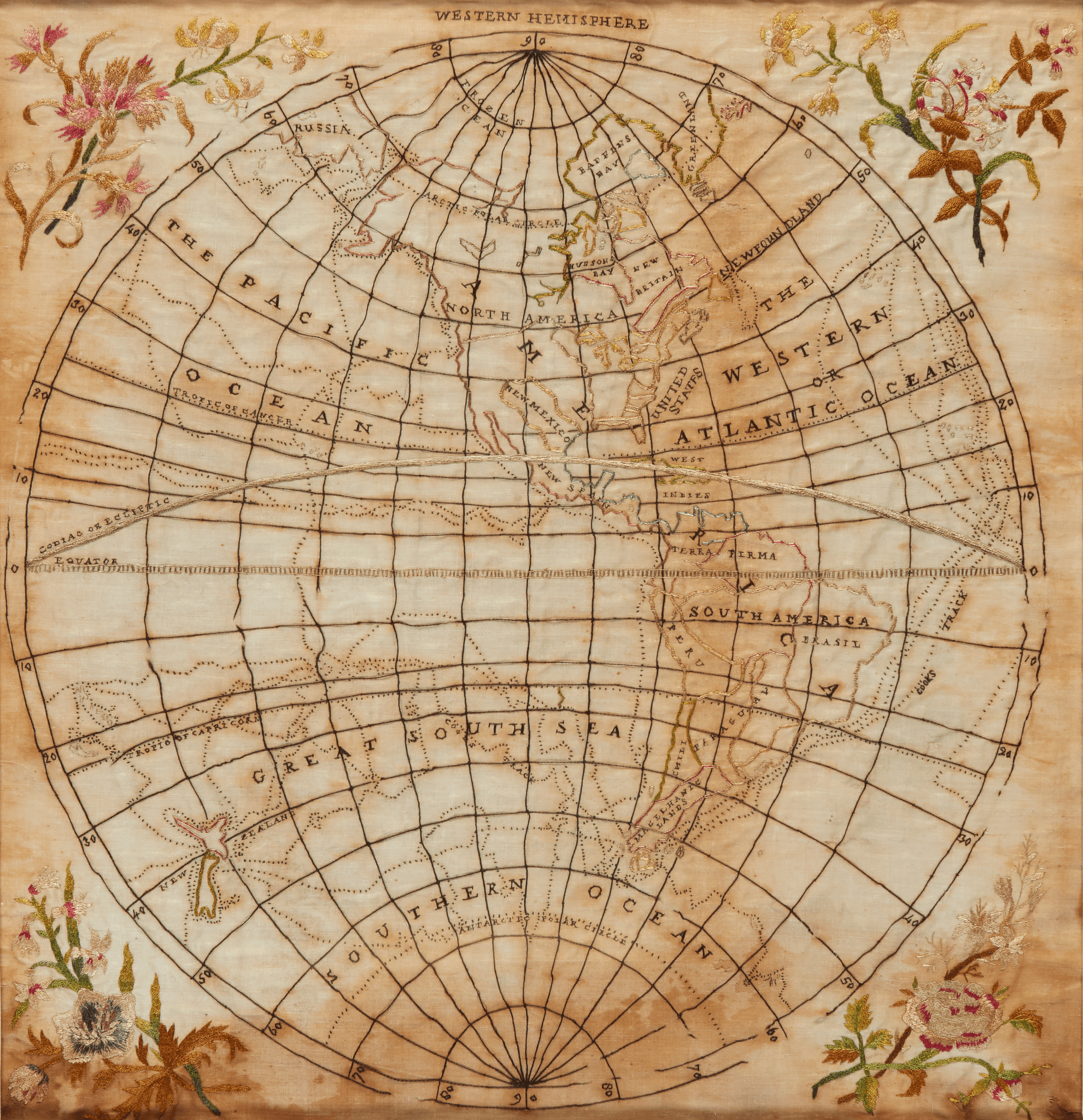 Embroidered map of the Western Hemisphere. countries and continents embroidered in various colours, longititude and latitude are marked, each of the four corners of the fabric is embroidered and depicts sprigs of flowers.