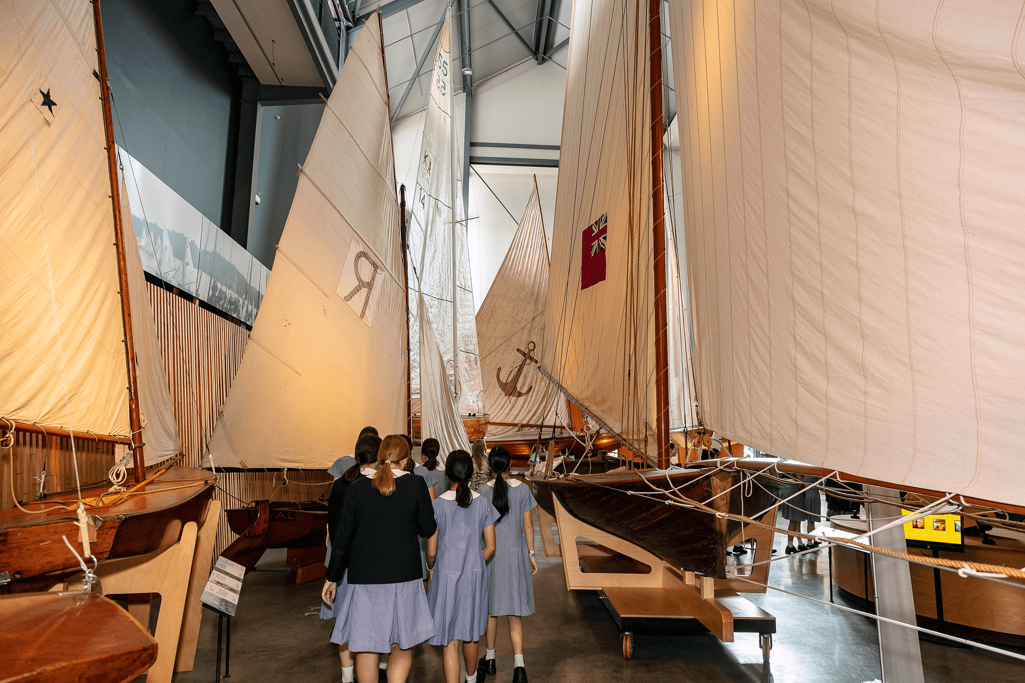 Photo of high school students walking between wooden sailing boats.