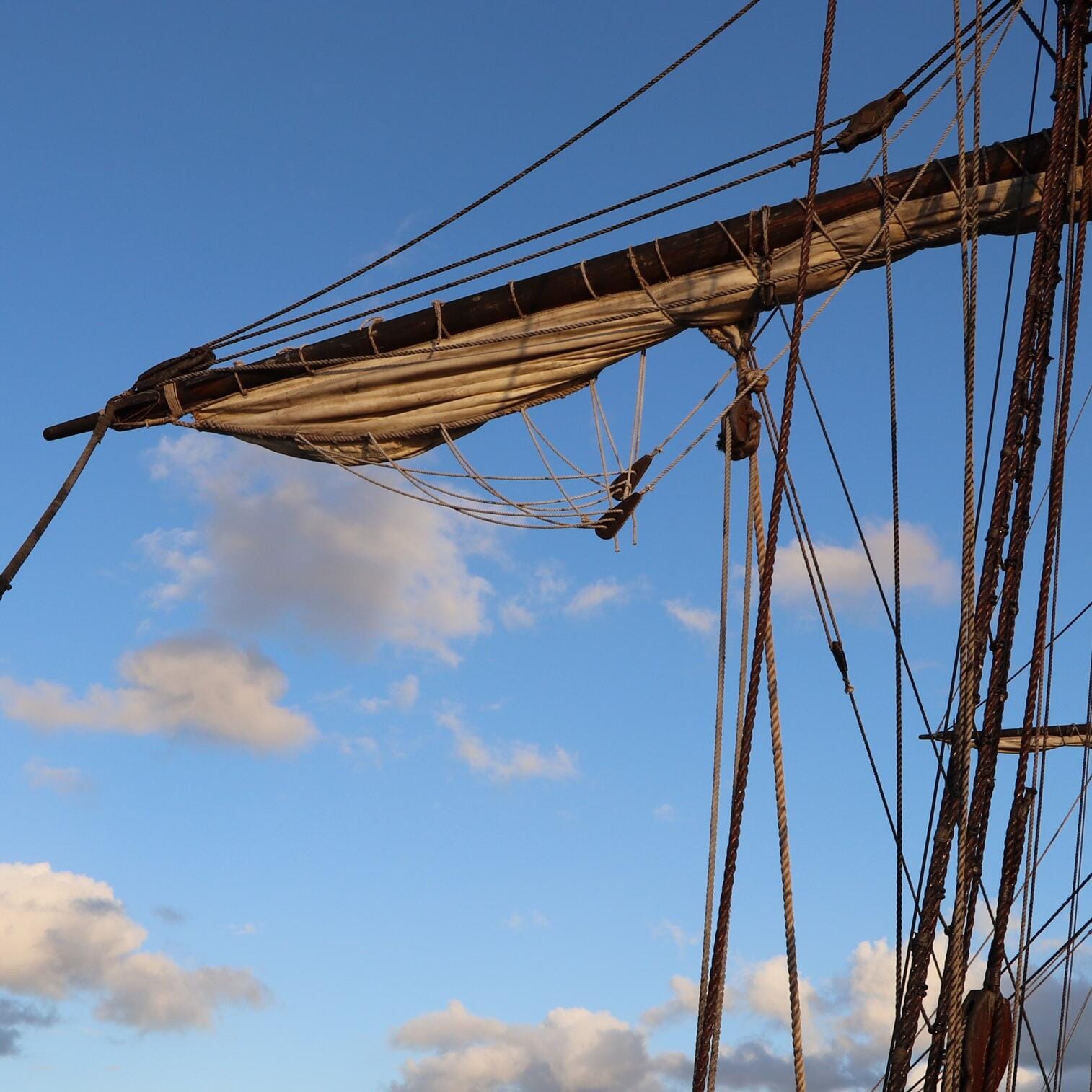 tall ship masts and rope with blue sky and clouds