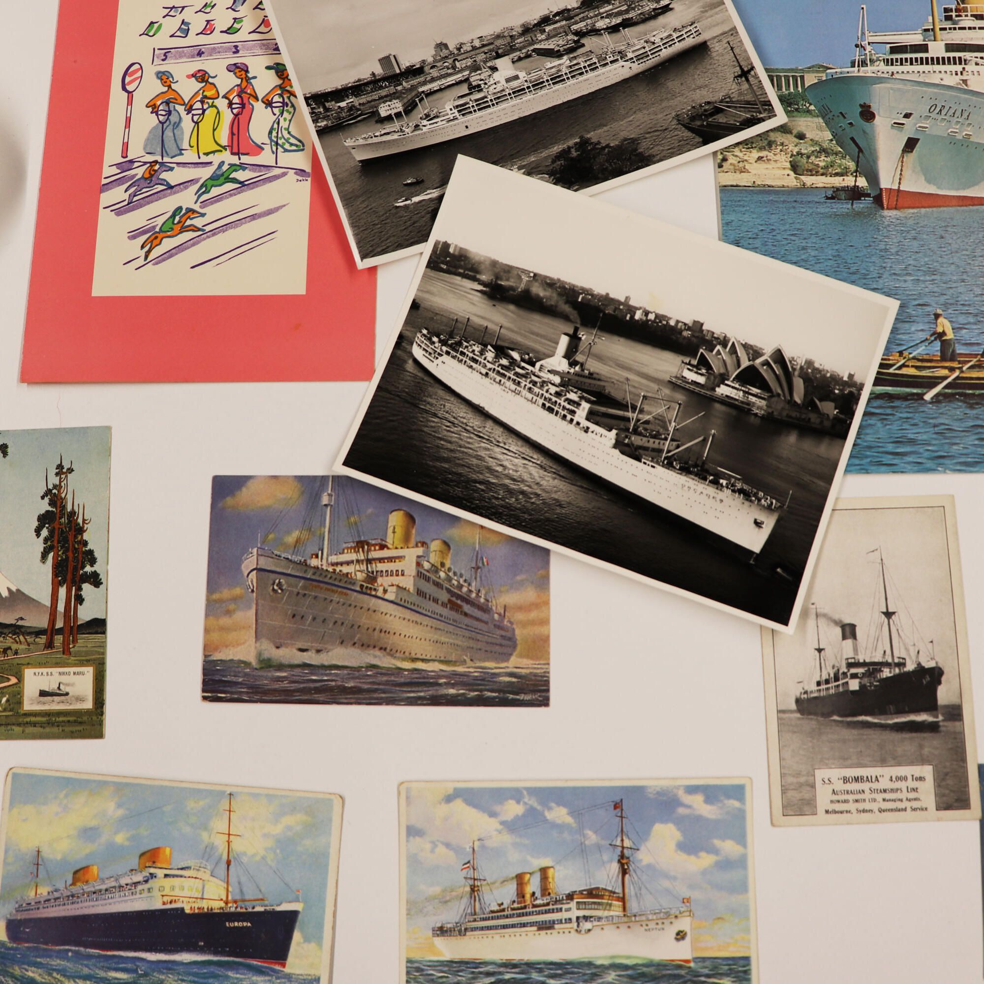 Selection of photos, postcards and illustrations on a white table.