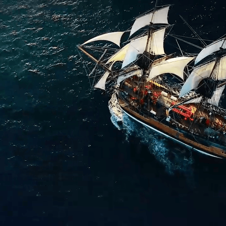 Overhear shot of replica Endeavour tall ship, sailing with large white sails on a dark blue green ocean.