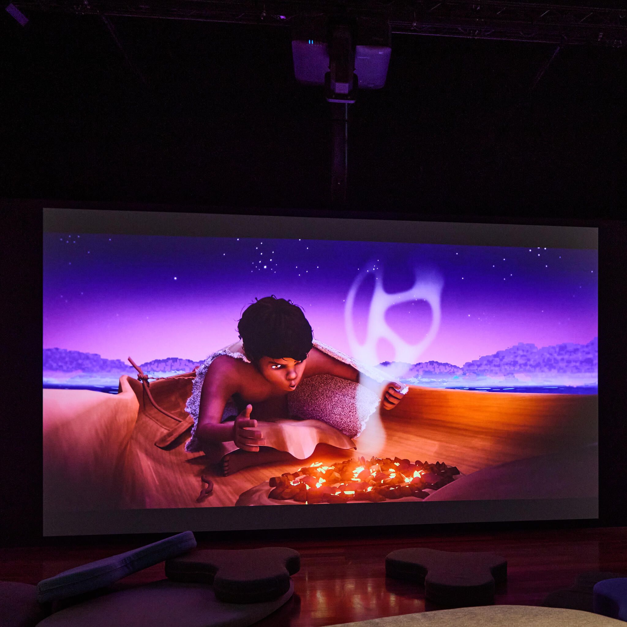 Photo of video work on a screen, showing an animation of an aborigional boy lighting a small fire