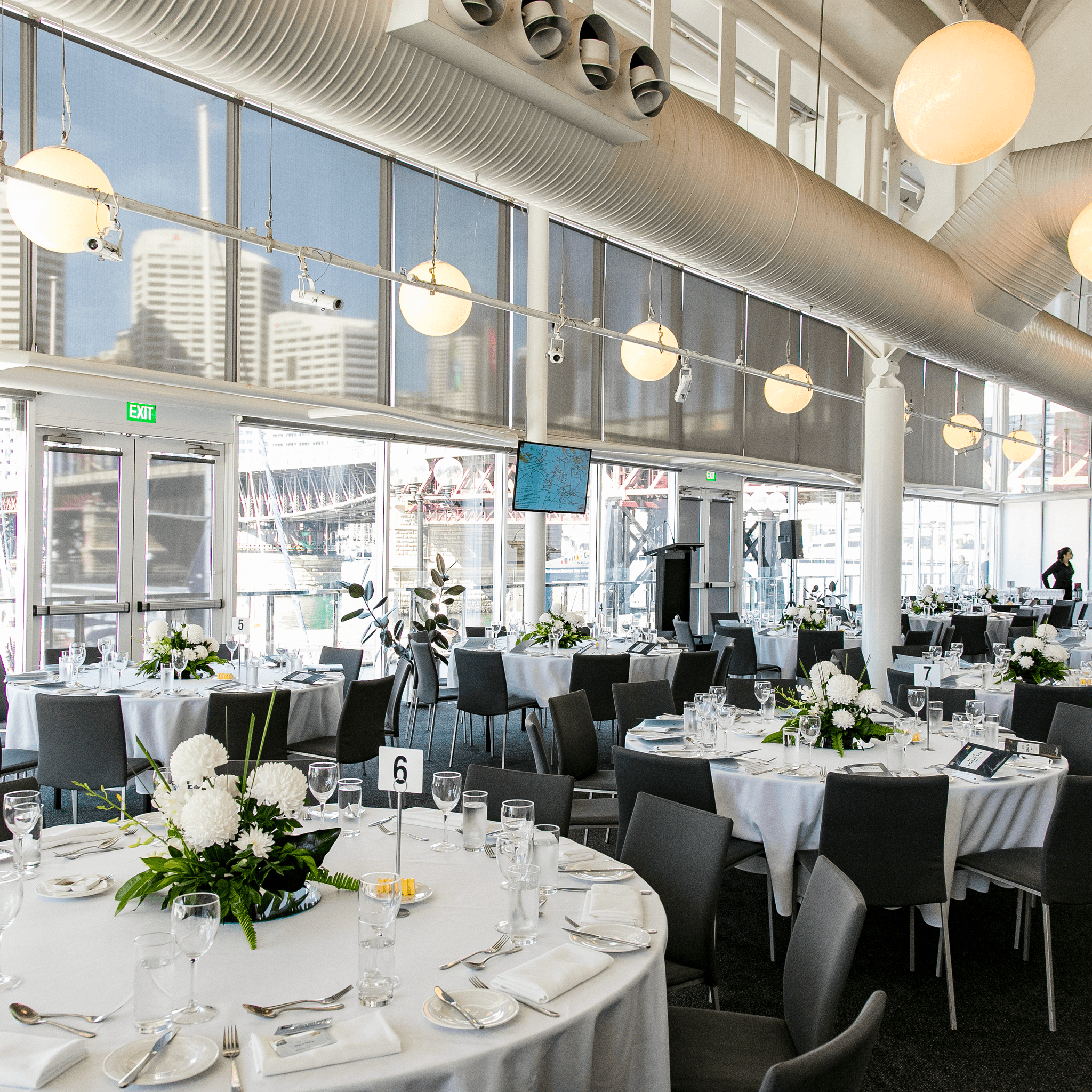 photo of a light filled event space with large round tables set for a formal event. 