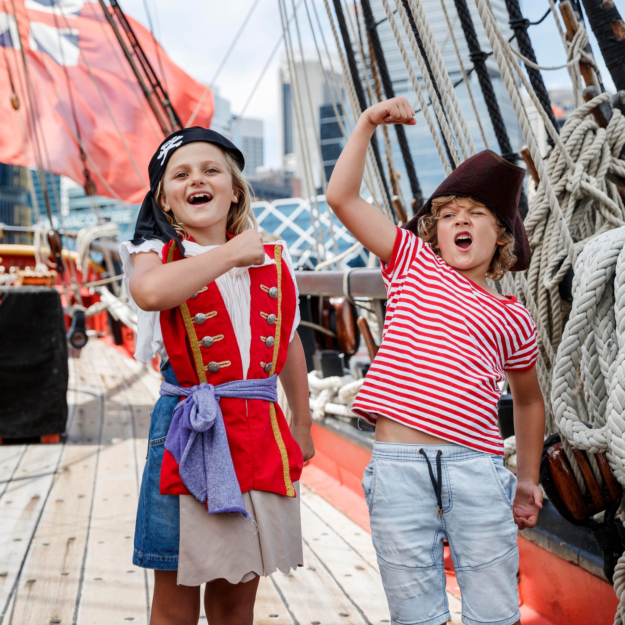 Two kids dressed up as pirates, the girl has a bandana and the boy has a pirate hat. 