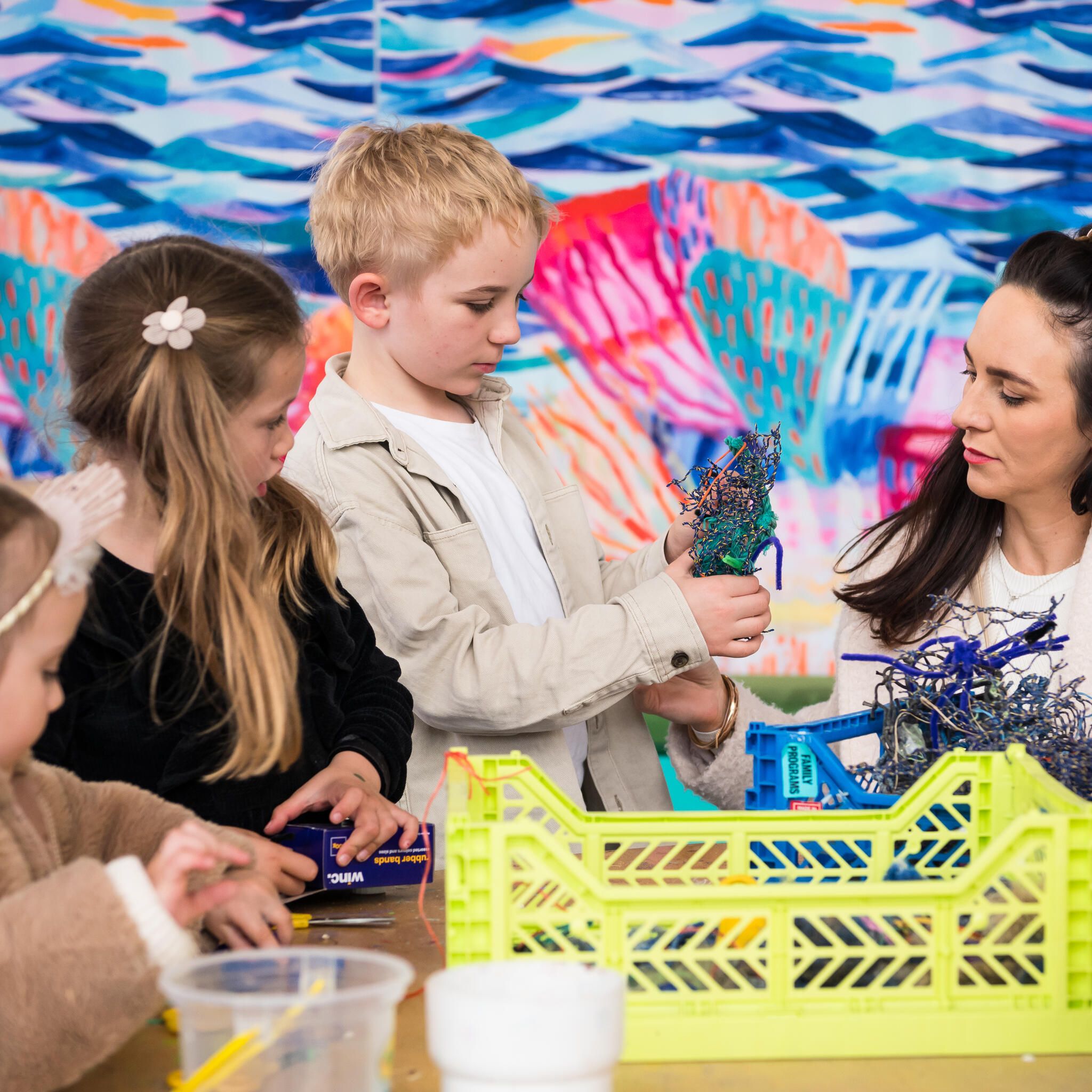 3 children and a women making craft with recycled materials.